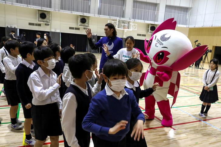 FILE PHOTO: Students Of Ariake Nishi Gakuen School Wear Protective Face Masks, Following The Outbreak Of The Coronavirus, As They Wave To A Para Athlete Chiaki Takada And Mascot Someity After An Event Six Months To Go Until Tokyo 2020 Paralympic Games In T